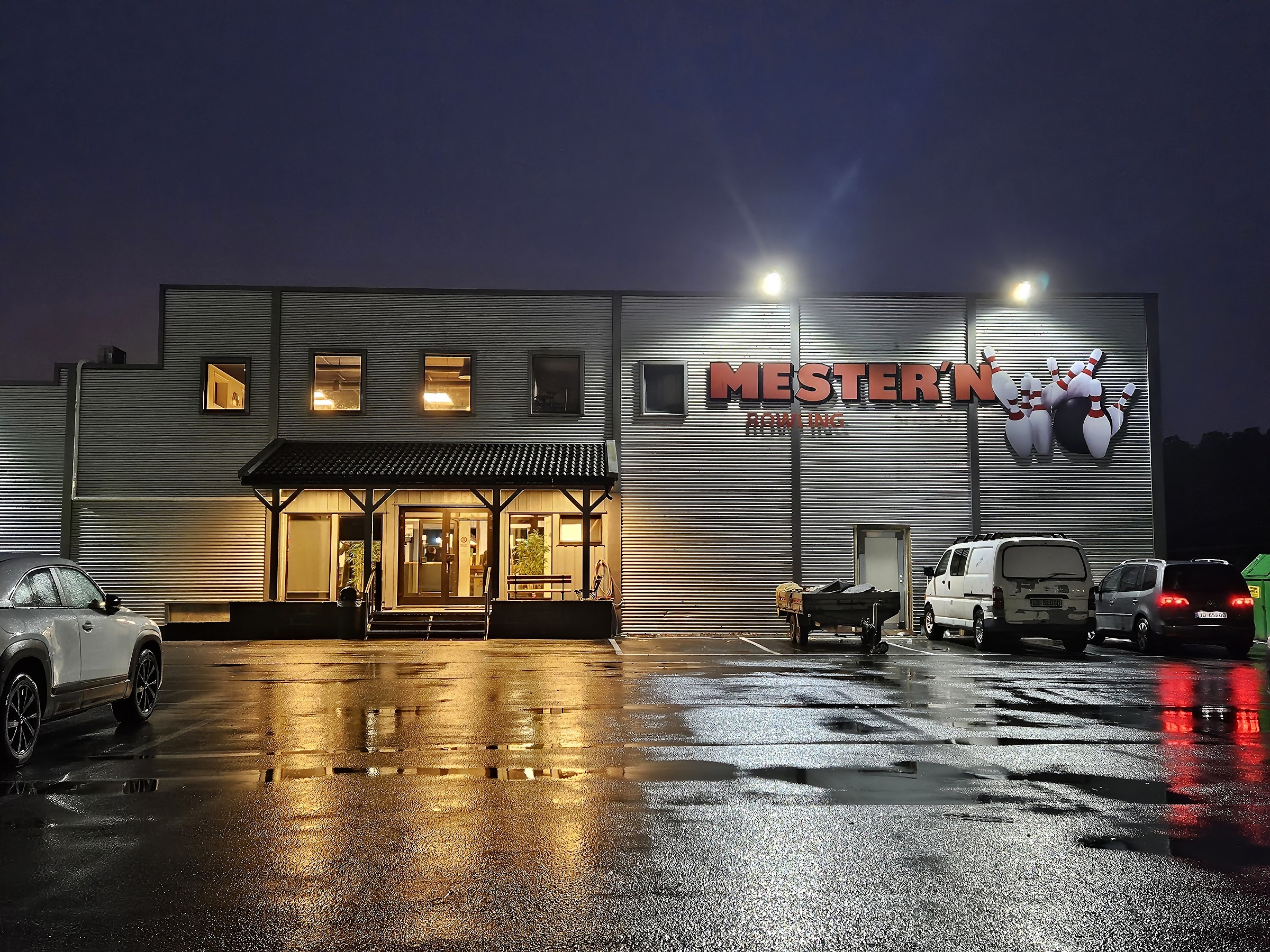 Mester'n Bowlings fasade om kvelden — opplyst MESTER'N-skilt med 3D-bowlingpinner